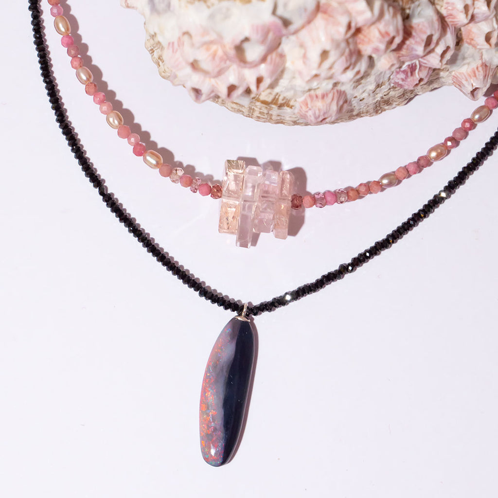 Discover the magic of Australian Black Opals. This incredibly chic necklace features a mesmerising organic cut opal with brilliant red, pink &amp; gold colour play.