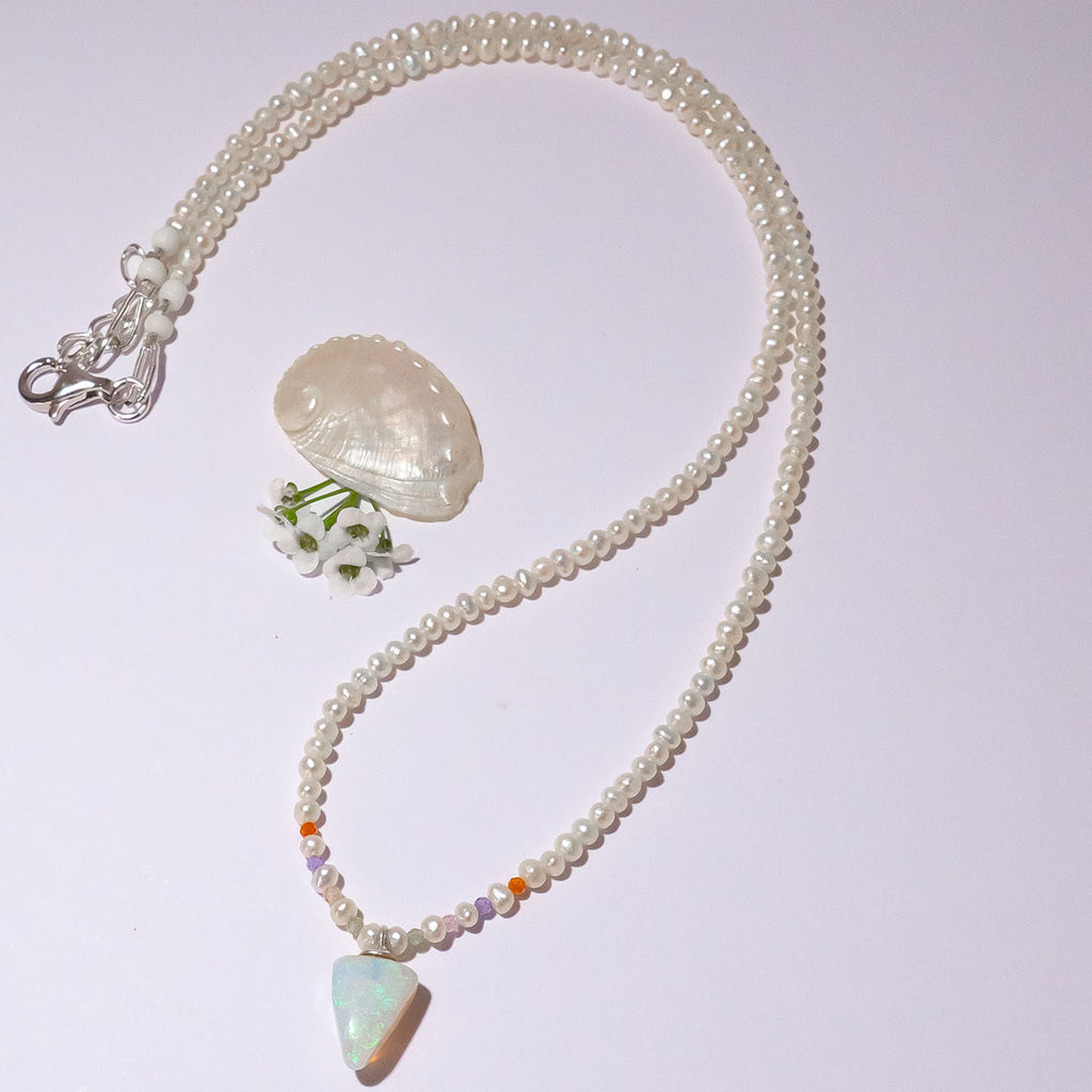 A pearl necklace with twist, we have added a tiny luminous crystal opal as the centrepiece.