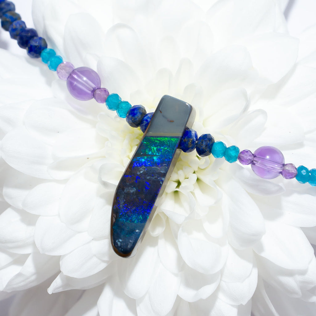 The wind passes over the outback in a streak of of blue, and a rolling flash of green. A solid opal with the intensity of bright colour that is absolutely unique, on a deep blue Lapis Lazuli faceted bead necklace.