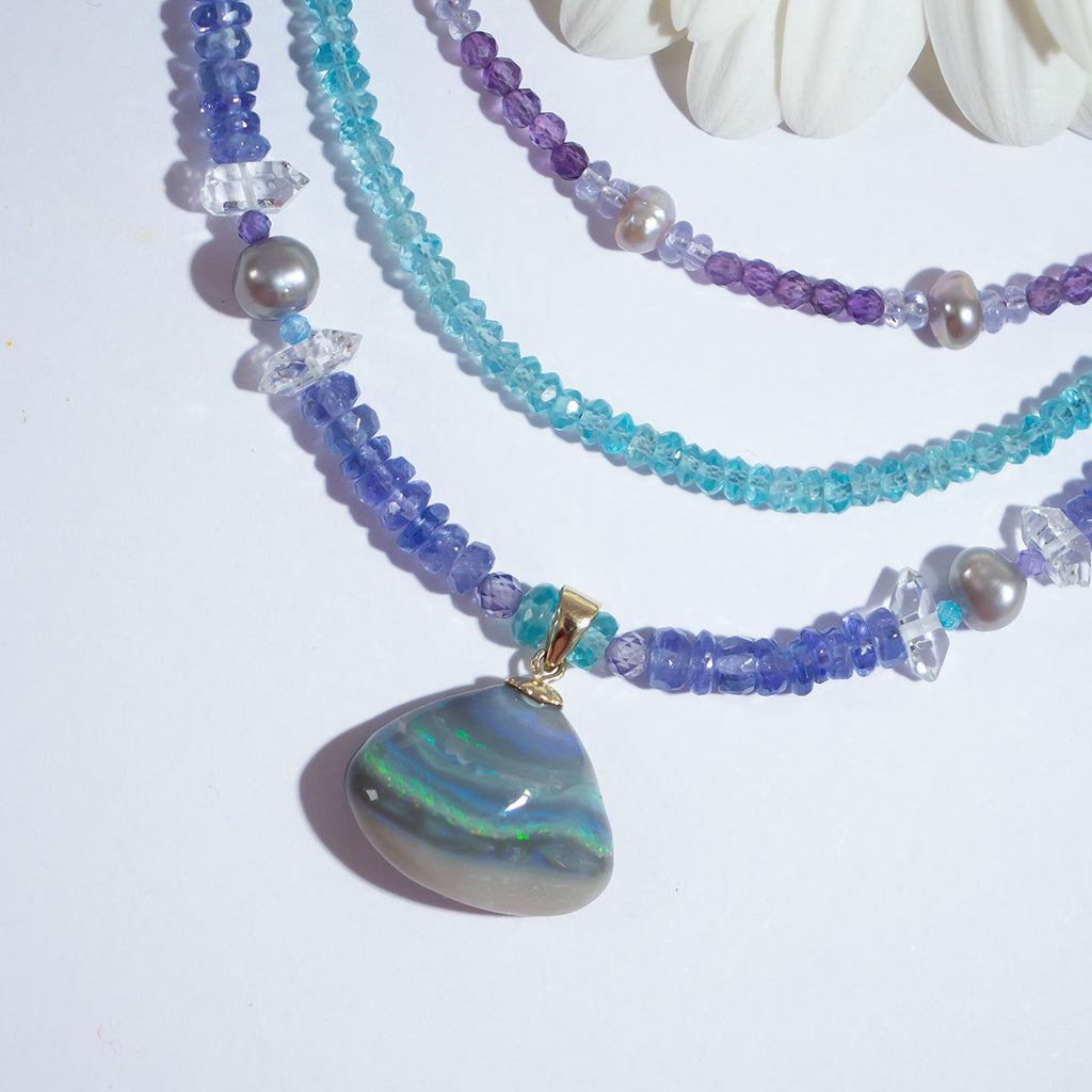 Misty grey, sparkling green, blue and gold rivers that dip and swirl across the opal, an enchanting Australian opal strung on a gorgeous Tanzanite gemstone necklace highlighted with soft grey pearls.